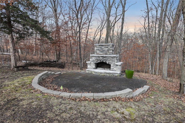 yard at dusk with an outdoor stone fireplace