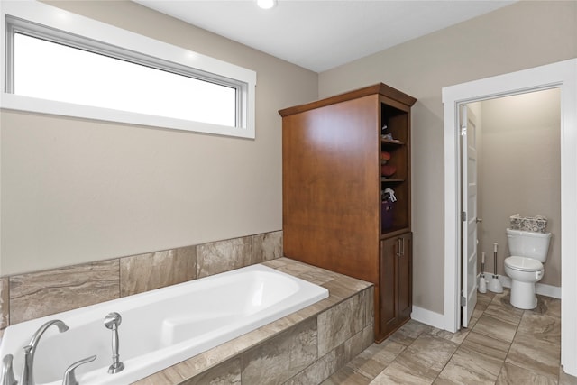 bathroom with toilet and tiled bath