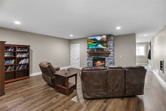 living room with hardwood / wood-style flooring and a stone fireplace