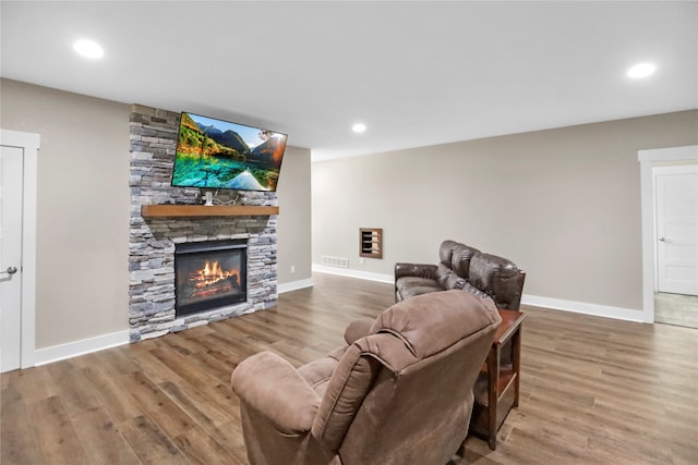 living room featuring a stone fireplace and hardwood / wood-style floors