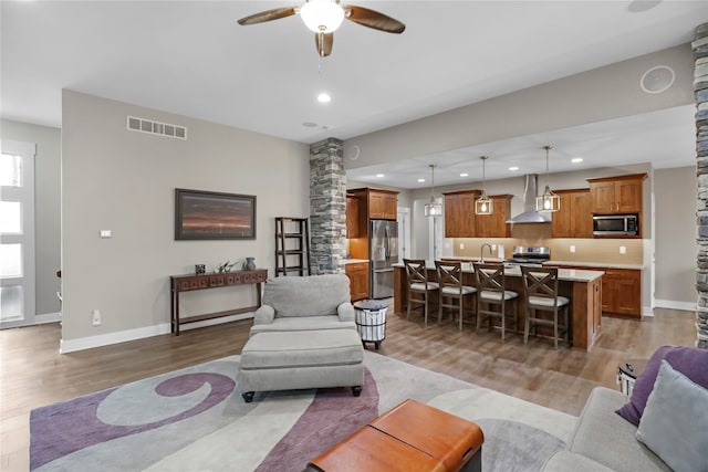 living room with ceiling fan, wood-type flooring, and decorative columns