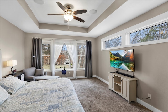 bedroom with ceiling fan, a raised ceiling, and light carpet