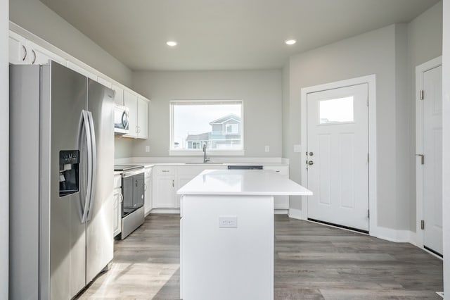 kitchen with light wood-type flooring, stainless steel appliances, sink, a center island, and white cabinetry