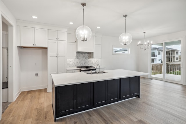 kitchen featuring a kitchen island with sink, sink, white cabinets, and a healthy amount of sunlight