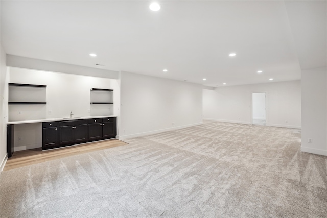 unfurnished living room with light colored carpet and sink