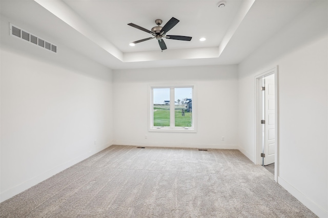 carpeted empty room with a tray ceiling and ceiling fan