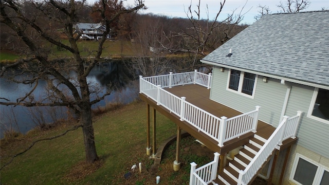 deck with a water view and a lawn