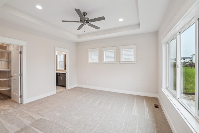 unfurnished bedroom featuring multiple windows, ensuite bathroom, and light colored carpet