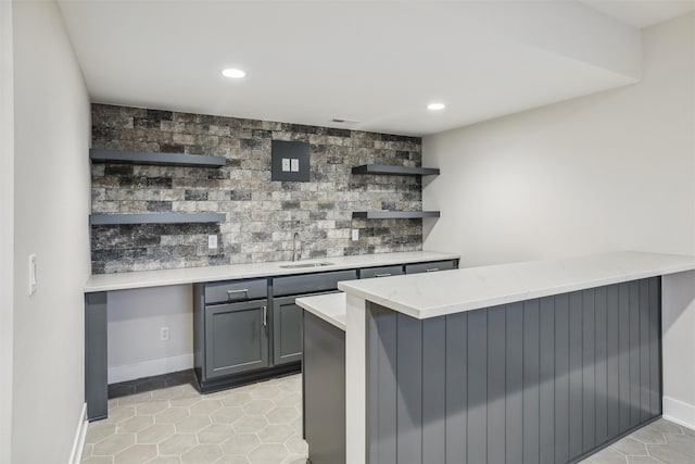 bar featuring gray cabinets, light tile patterned flooring, sink, and tasteful backsplash