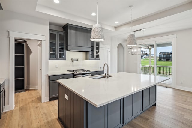 kitchen featuring gas stove, sink, light hardwood / wood-style flooring, a spacious island, and decorative light fixtures