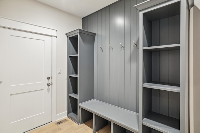 mudroom with wood walls and light wood-type flooring