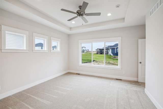 carpeted empty room featuring a tray ceiling and ceiling fan