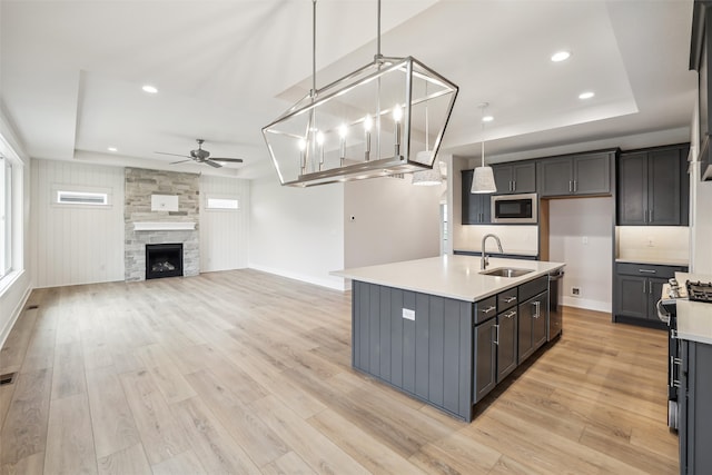 kitchen featuring decorative light fixtures, stainless steel appliances, light hardwood / wood-style flooring, and a kitchen island with sink