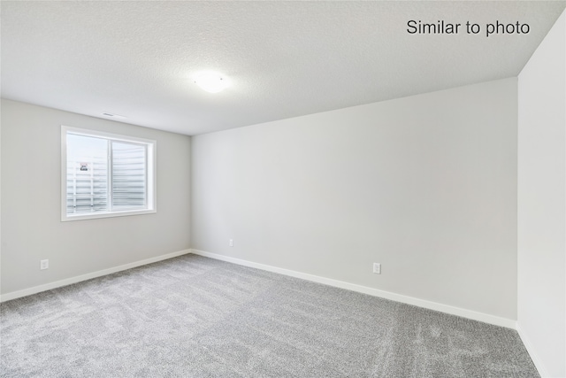 spare room featuring carpet flooring and a textured ceiling