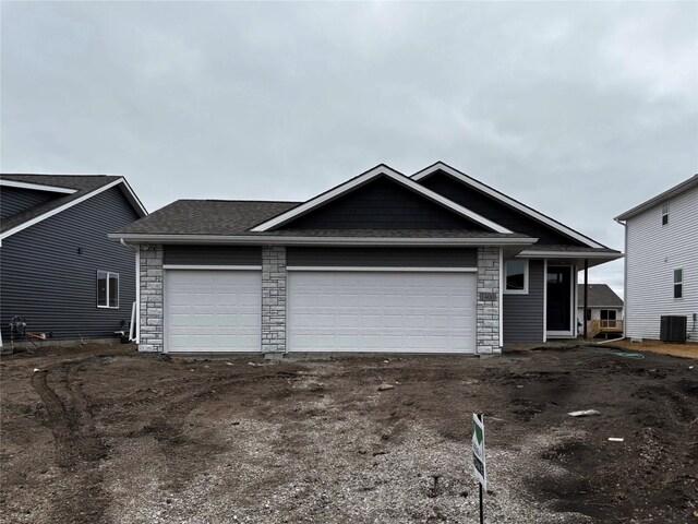 view of front of house featuring driveway, cooling unit, stone siding, and an attached garage