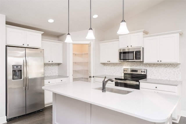 kitchen featuring appliances with stainless steel finishes, decorative light fixtures, white cabinetry, and an island with sink