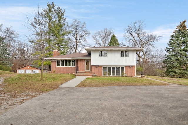 tri-level home with an outdoor structure, a front yard, and a garage