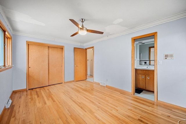 unfurnished bedroom featuring ensuite bathroom, ornamental molding, ceiling fan, light hardwood / wood-style floors, and a closet