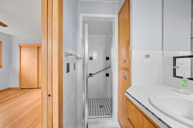 bathroom with vanity, a shower with shower door, and ornamental molding