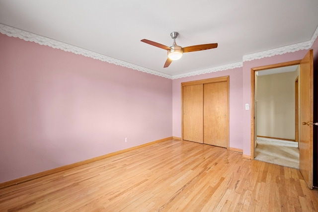 unfurnished bedroom featuring ceiling fan, light wood-type flooring, ornamental molding, and a closet