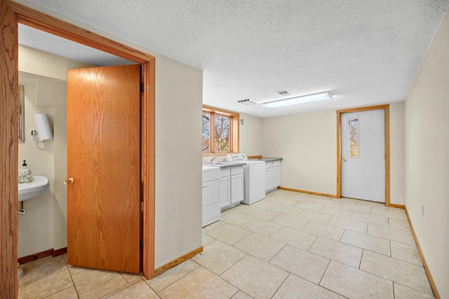 laundry room featuring washer / clothes dryer, light tile patterned flooring, and a textured ceiling