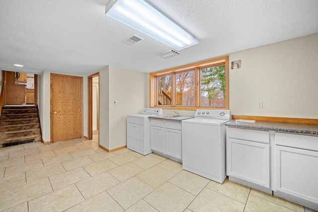 laundry area featuring cabinets, a textured ceiling, sink, washing machine and clothes dryer, and light tile patterned flooring