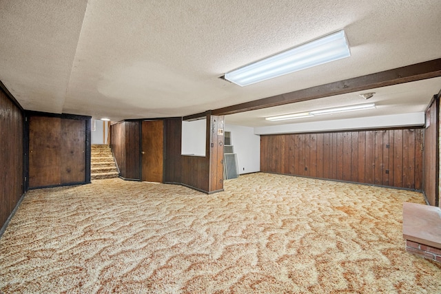 additional living space featuring wooden walls, light colored carpet, and a textured ceiling