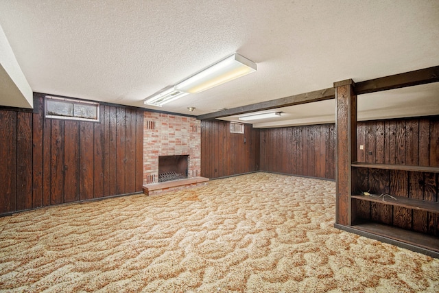 basement with wood walls, light colored carpet, a textured ceiling, and a brick fireplace