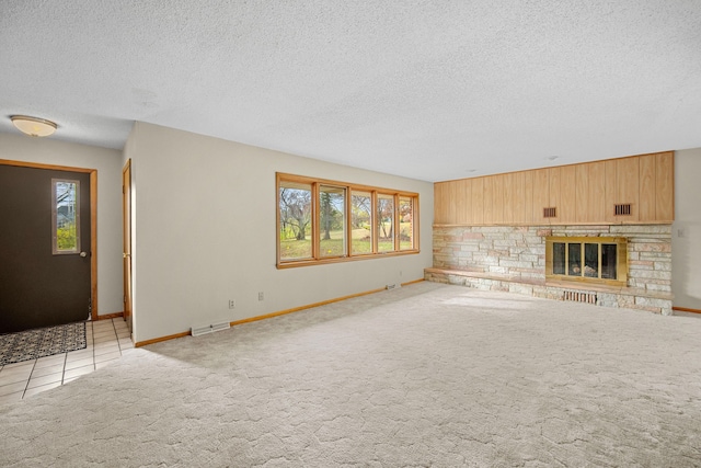 unfurnished living room featuring a textured ceiling, light colored carpet, and a stone fireplace