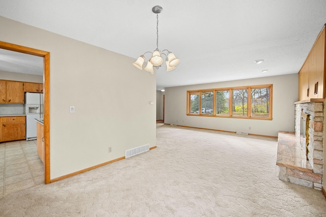 unfurnished living room with a fireplace, light colored carpet, a textured ceiling, and a notable chandelier