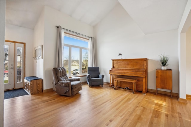 sitting room with high vaulted ceiling and light wood-type flooring