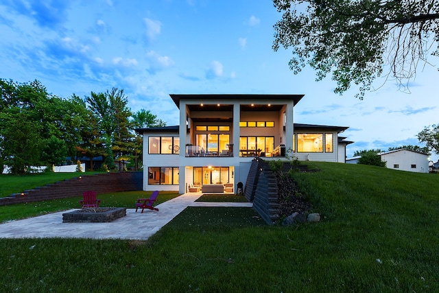 rear view of house with a yard, a patio area, a balcony, and an outdoor fire pit