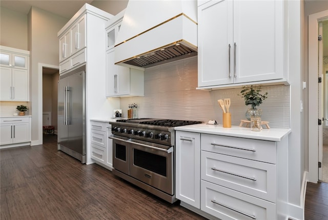 kitchen with dark hardwood / wood-style flooring, premium range hood, decorative backsplash, white cabinets, and high end appliances