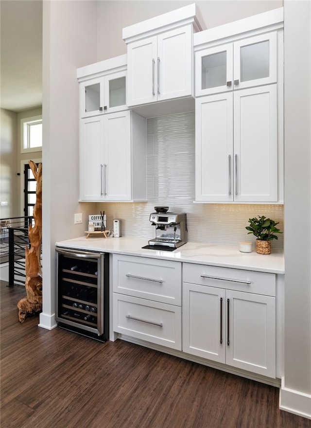 bar with white cabinets, dark hardwood / wood-style flooring, backsplash, and beverage cooler