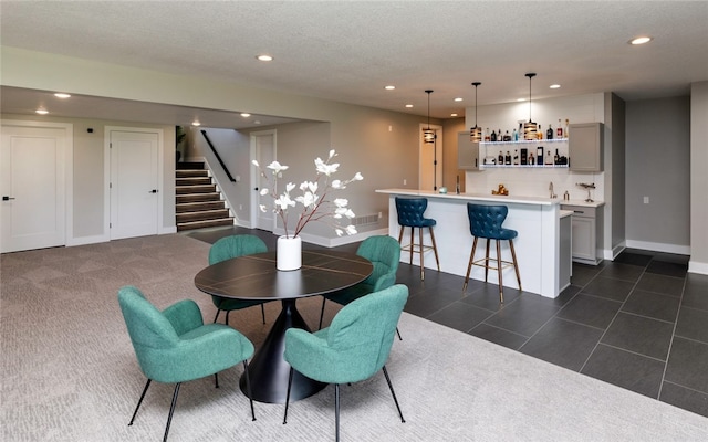 tiled dining area with a textured ceiling and indoor bar