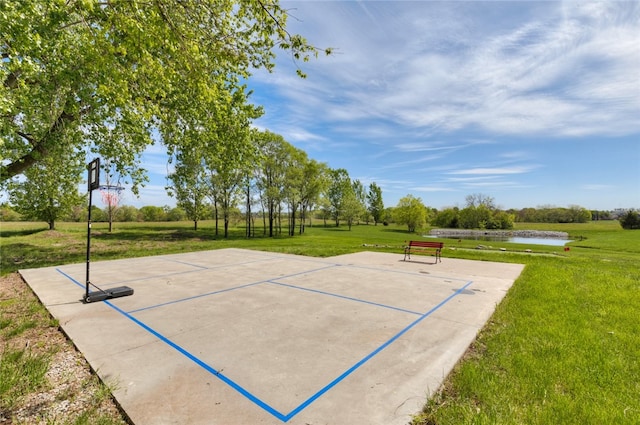 view of community featuring basketball court, a yard, and a water view