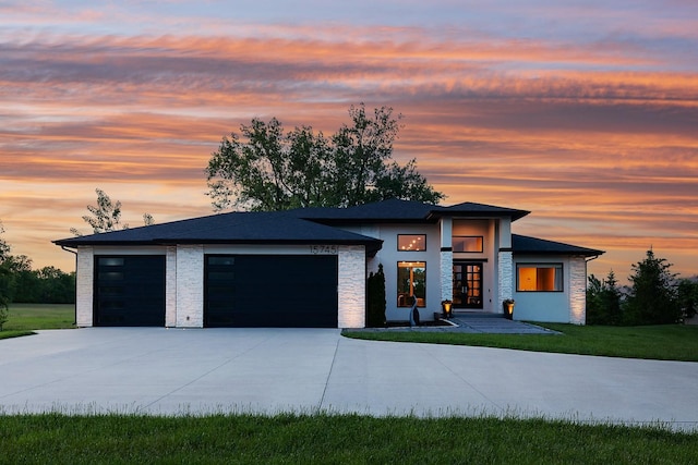 prairie-style house featuring a lawn and a garage