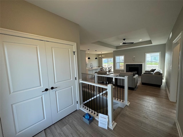 corridor featuring a raised ceiling, hardwood / wood-style floors, a chandelier, and sink