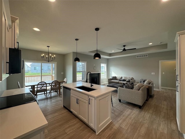 kitchen featuring sink, stainless steel dishwasher, light wood-type flooring, an island with sink, and white cabinetry