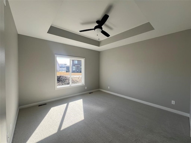 spare room with carpet flooring, a tray ceiling, and ceiling fan