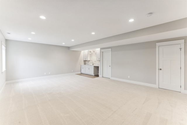 basement featuring sink and light carpet