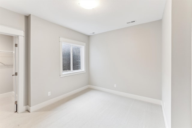 unfurnished bedroom with a walk in closet, light carpet, and a closet