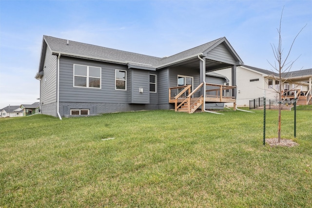 rear view of house featuring a wooden deck and a yard