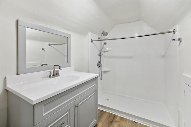 bathroom with vaulted ceiling, a shower, hardwood / wood-style floors, and vanity