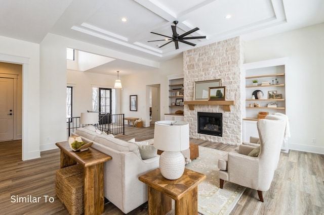 living room with ceiling fan, coffered ceiling, beamed ceiling, hardwood / wood-style floors, and a fireplace