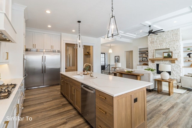 kitchen with appliances with stainless steel finishes, sink, a center island with sink, dark hardwood / wood-style floors, and white cabinetry