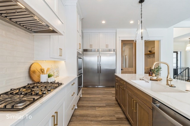 kitchen with sink, dark wood-type flooring, stainless steel appliances, premium range hood, and white cabinets