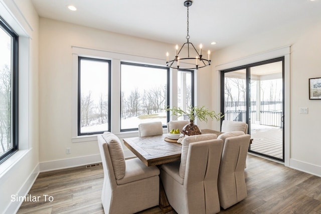 dining room featuring a wealth of natural light, wood-type flooring, and a notable chandelier