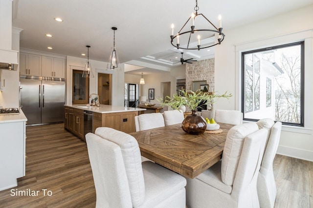 dining room with ceiling fan with notable chandelier, dark wood-type flooring, sink, beamed ceiling, and a fireplace