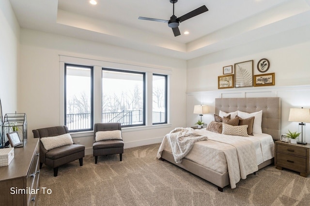 carpeted bedroom featuring a tray ceiling and ceiling fan